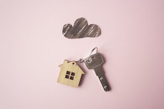 Paper dark cloud above the wooden house and key. Bad times, mortgage, no money concept. Flat lay. Top view