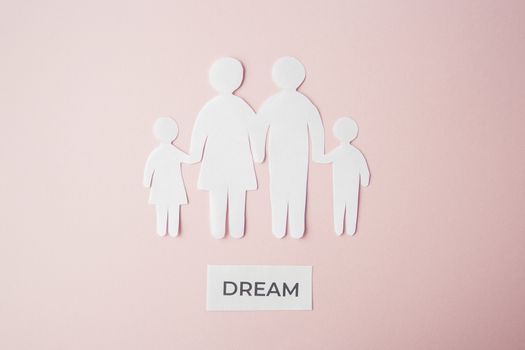 paper family cut out on bright pink background, family home, foster care, family dream, loneliness, life concept. Paper family with phrase quote Dream 