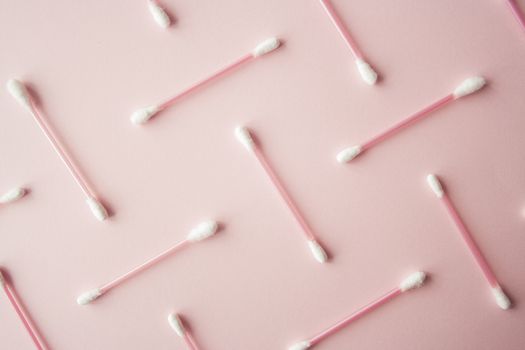 Flat lay cotton buds on pink warm background. Pattern of cotton swubs, beauty and health care concept. Cotton composition