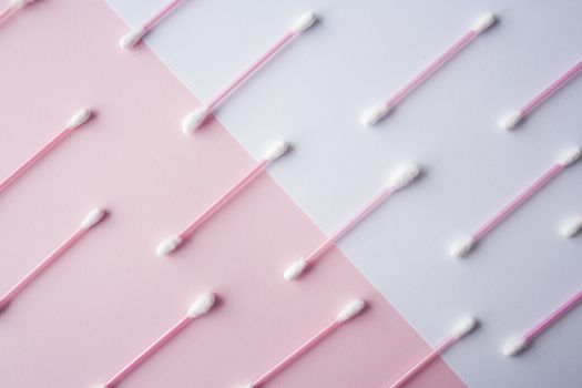 Flat lay cotton buds on pink warm and blue background. Pattern of cotton swubs, beauty and health care concept. Cotton composition