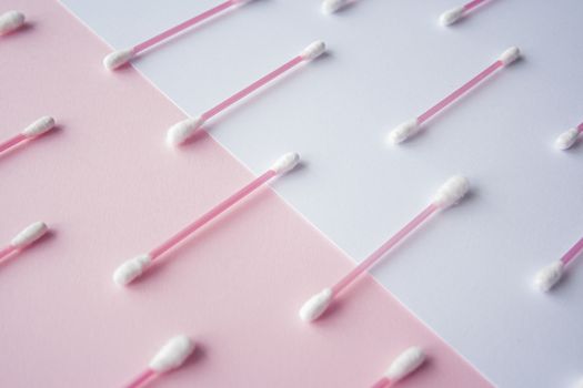 Flat lay cotton buds on pink warm and blue background. Pattern of cotton swubs, beauty and health care concept. Cotton composition