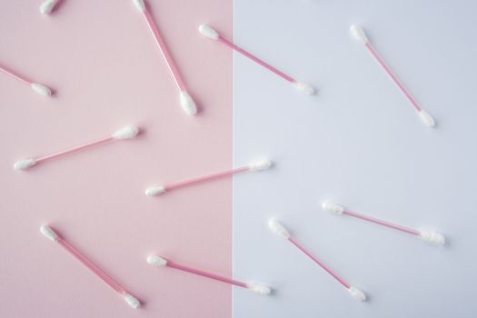 Flat lay cotton buds on pink warm and blue background. Pattern of cotton swubs, beauty and health care concept. Cotton composition