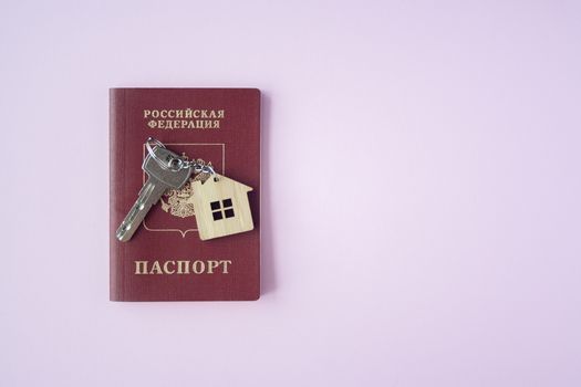 Russian international Passport and key  with trinket house on it on pink background close up copy space. Immigration, emigration, citizenship concept