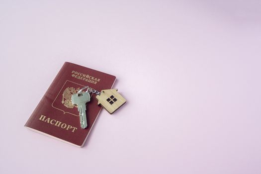 Russian international Passport and key  with trinket house on it on pink background close up copy space. Immigration, emigration, citizenship concept