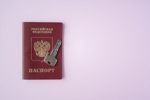 Russian international Passport and key  with trinket house on it on pink background close up copy space. Immigration, emigration, citizenship concept