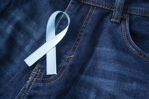 Prostate Cancer Awareness, light Blue Ribbon on male jeans fly background. Closeup, hope, cure, treatment, medical symbol. Blue ribbon on men crotch