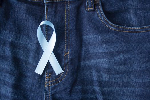 Prostate Cancer Awareness, light Blue Ribbon on male jeans fly background. Closeup, hope, cure, treatment, medical symbol. Blue ribbon on men crotch