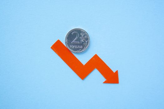 two rouble coin on blue background with red arrow down. exchange rate chart. ruble depreciation. Exchange rate of rouble fall. Rouble to dollar