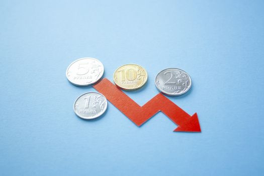 many rouble coins on blue background with red arrow down. exchange rate chart. ruble depreciation. Exchange rate of rouble fall. Rouble to dollar