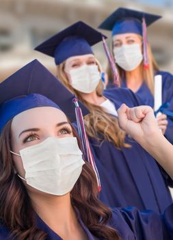 Several Female Graduates in Cap and Gown Wearing Medical Face Masks.