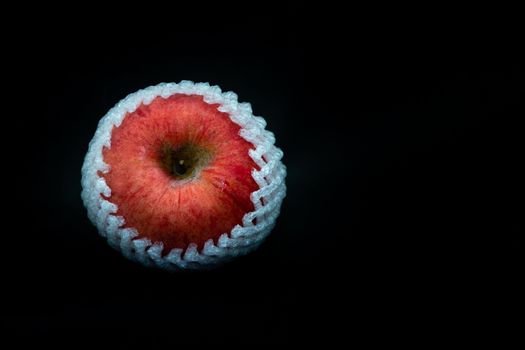A fresh red apple with Shockproof sponge against black background with space for text