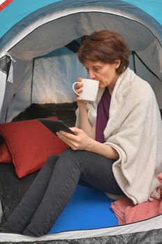 Quarantine At Home. Woman sit inside a tent enjoying a cup of tea