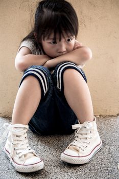 A Lonely girl sitting behind the concrete wall