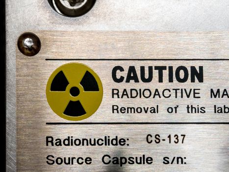 Radiation warning sign on the nameplate and the machanical container of factory process instrument, Ionizing radiation hazard symbol as background