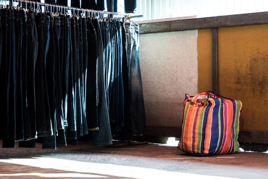 Multi color on Plastic sack and the row of denim pants hanging on trempels. Jeans in clothing store