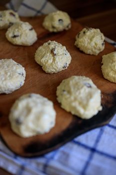 On the board prepared for frying Russian traditional home-made cottage cheese pancakes with raisins - cheesecakes on a wooden table.