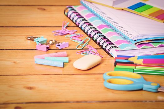 Close up shot of pastel colored girl school stationary on wooden background. Back to school concept.