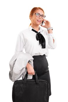 Smiling beautiful young businesswoman with glasses in a suit talking on the phone, holding a laptop bag, isolated on a white background. Business communication concept.