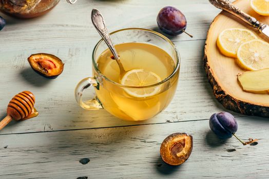 Cup of tea with lemon, honey and ginger over wooden surface