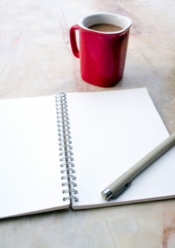 The blank page of a spiral notebook and coffee cup