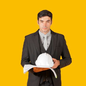 Young businessman in a gray shirt and black suit holding a white construction hat and the construction drawings. The concept of investing in good business. Portrait with studio light.