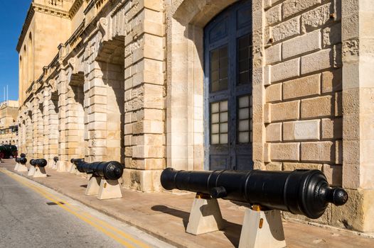 Old cannons lined up in front of the facade of the marine museum in Malta