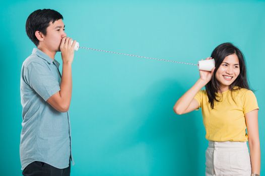 Asian happy young couple beautiful handsome smile and talking together with paper can telephone in a studio shot on blue background with copy space for text