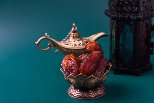 Ramadan Kareem fasting Food Concept, Bronze plate dates, and lantern Aladdin lamp decoration, eid Arabian Muslim religious festival on a dark green background with copy space for text