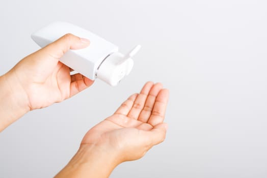 Closeup Hand Asian young woman applying drop dispenser sanitizer alcohol gel on hand wash cleaning, hygiene prevention COVID-19 or coronavirus protection concept, isolated on white background