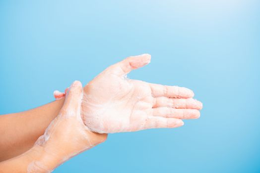 Closeup body care Asian young woman washing hands with soap have foam, hygiene prevention COVID-19 or coronavirus protection concept, isolated on blue background
