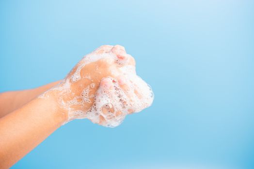 Closeup body care Asian young woman washing hands with soap have foam, hygiene prevention COVID-19 or coronavirus protection concept, isolated on blue background
