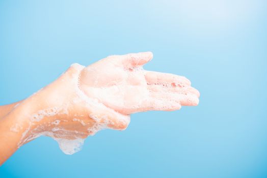 Closeup body care Asian young woman washing hands with soap have foam, hygiene prevention COVID-19 or coronavirus protection concept, isolated on blue background