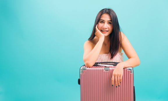 Portrait asian beautiful woman her sitting with travel bag on weekends on blue background, with copy space for text