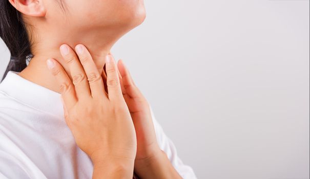 Asian beautiful woman Sore Throat or thyroid gland problem her useing Hand Touching Ill Neck on white background with copy space, Medical and Healthcare concept