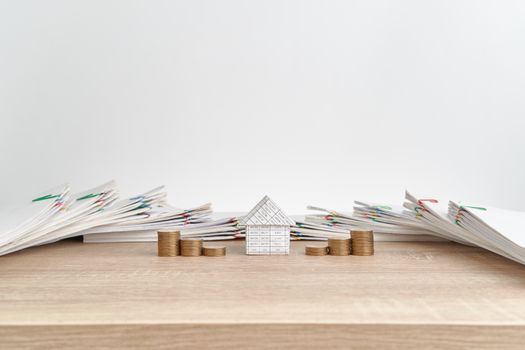 House between step pile of gold coins on wooden table have pile of paperwork of report of sale and receipt as background and copy space. Business and finance concepts rich and successful photography.