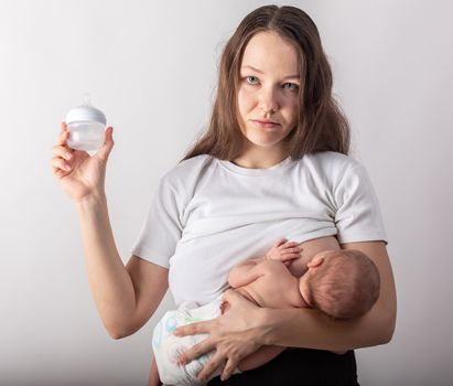 A mother breastfeeds a baby, not a bottle. Natural feeding concept