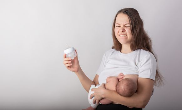 A mother breastfeeds a baby, not a bottle. Natural feeding concept