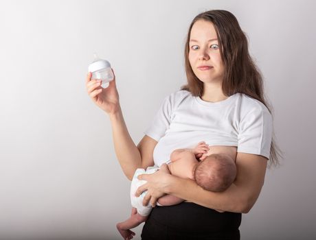 A mother breastfeeds a baby, not a bottle. Natural feeding concept