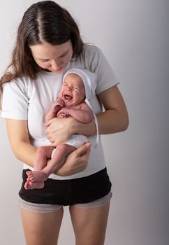 Newborn baby cries in the arms of his mother.