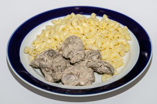 Chicken liver stewed in sour cream and a side dish of pasta in a bowl on a white background, close-up. healthy food, menu concept background