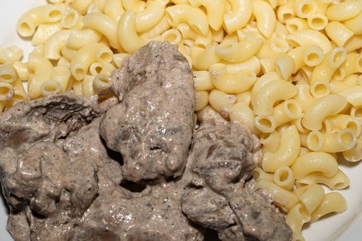 Chicken liver stewed in sour cream and a side dish of pasta in a bowl , close-up. healthy food, menu concept background