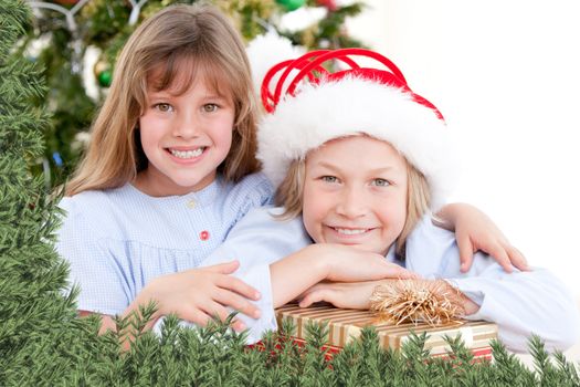 Composite image of adorable childrens celebrating christmas  against green fir branches