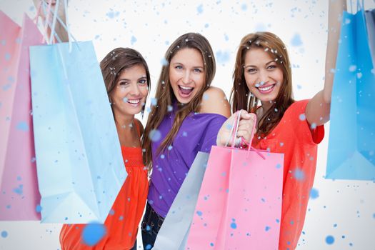 Three teenagers raising their arms while holding their purchases against snow falling