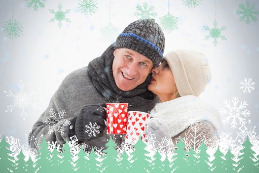 Happy mature couple in winter clothes holding mugs against snowflakes and fir trees in green
