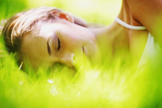 Beautiful young woman sleep on green spring grass