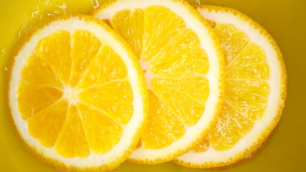 Sliced orange backgroundjuicy orange slices on yellow background with drops of moisture