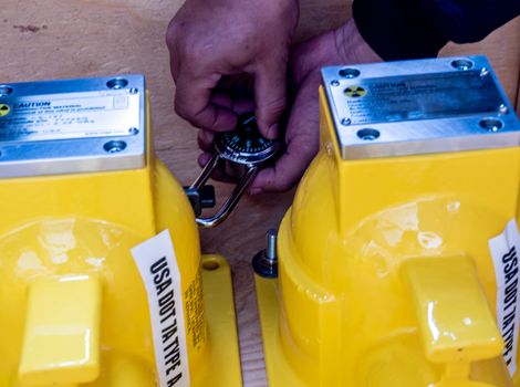 The worker spins the padlock code to unlock the mechanical shutter of the new container of the nuclear base instrument