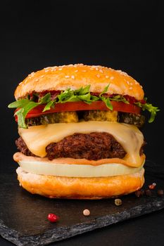 One big tall classic hamburger burger cheeseburger on black background