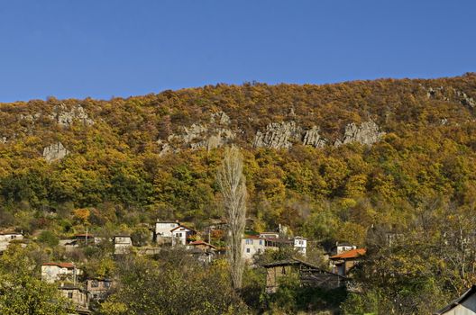 Amazing autumn view of glade, hill, forest with deciduous trees and residential district of the pretty village Zhrebichko, Bratsigovo municipality,  Rhodope mountains, Bulgaria