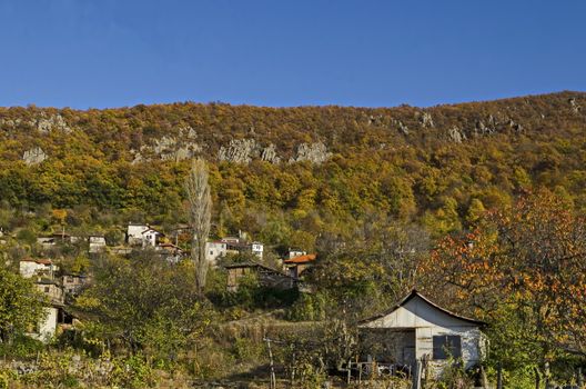 Amazing autumn view of glade, hill, forest with deciduous trees and residential district of the pretty village Zhrebichko, Bratsigovo municipality,  Rhodope mountains, Bulgaria